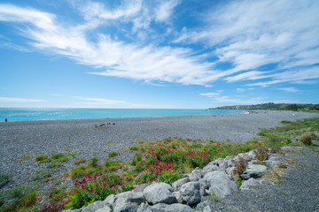 Stony Kaikoura beach and sea under blue sky with white clouds