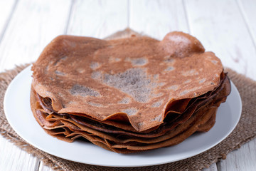Thin chocolate pancakes on a white plate