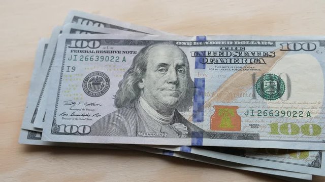 US 100 dollar bills being laid out and counted on a table