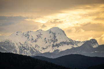 Fototapeta na wymiar Sunset over snow covered mountain Mittagskogel on cloudy sprint day