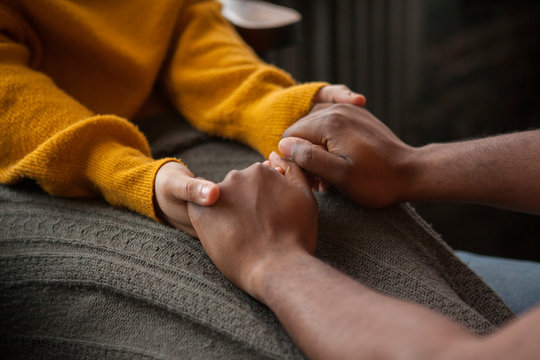 Cropped image of boyfriend holding girlfriend's hands sitting at home