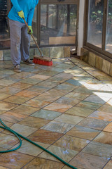 Housekeeper washes external verandah with water image with copy space in portrait format