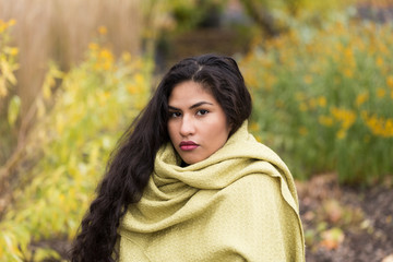 Horizontal portrait of sultry hispanic young woman with long curly dark hair draped in pale green...
