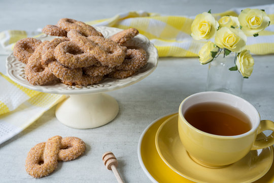 typical Dutch biscuit called Krakeling, on white cake stand. yellow cup of tea