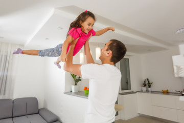 Happy family. Young father playing silly with his daughter lifting her up