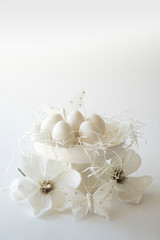 white romantic Easter scene, cake stand with eggs and flowers, against white background, space for text