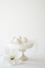 white romantic Easter scene, cake stand with eggs and flowers, against white background, space for text