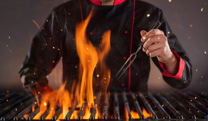 Closeup of chef holding fork above the grill