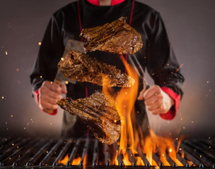Flying beef steaks above the grill