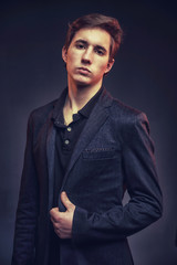 Portrait of an expressive, stylish, young man in a strict suit in orange tones with a smoky...
