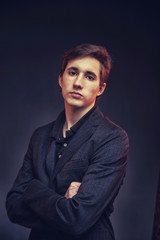 Portrait of an expressive, stylish, young man in a strict suit in orange tones with a smoky background