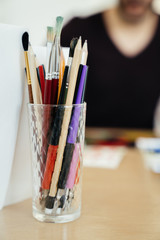 glass with pens and pencils on the table in the classroom for learning to draw.