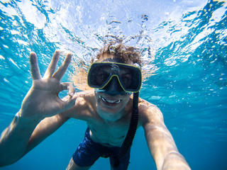 Selfie of young man snorkeling in the sea. Making everything ok symbol
