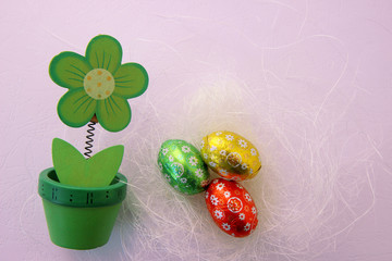 Сolorful Easter eggs in a nest on a pink background. Space for text