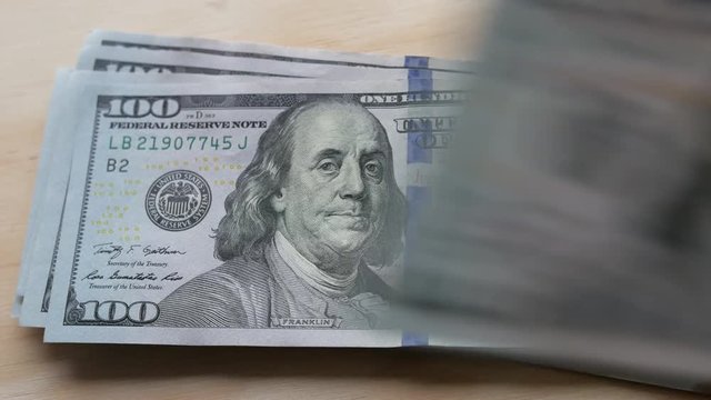 US 100 dollar bills being laid out and counted fast on a table