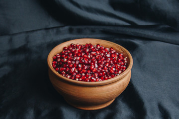 pomegranate grains in a ceramic bowl on a black fabric background, pomegranate fruit, ceramic jug, ceramic plate, isolated still life close up