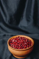 pomegranate grains in a ceramic bowl on a black fabric background, pomegranate fruit, ceramic jug, ceramic plate, isolated still life close up