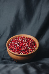 pomegranate grains in a ceramic bowl on a black fabric background, pomegranate fruit, ceramic jug, ceramic plate, isolated still life close up