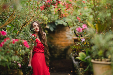 Young beautiful caucasian woman in glass greenhouse among colorful azalea flowers. Art portrait of...
