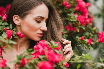 Young beautiful caucasian woman in glass greenhouse among colorful azalea flowers. Art portrait of...