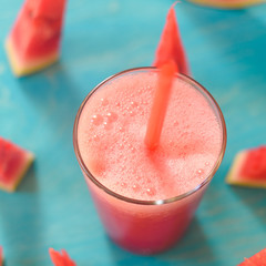 smoothie with watermelon on a turquoise background in a glass with a slice of watermelon with copy space, top view