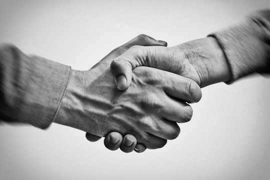 A firm handshake between two partners. Black and white image.
