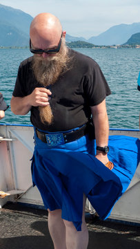 Mann mit langem Bart und Sonnenbrille tr&auml;gt einen Kilt, Schottenrock, der im Wind flattert