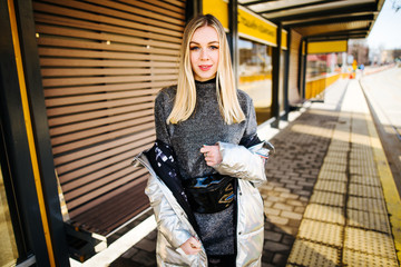 young beautiful girl in jacket walking along city street, woman is relaxing outdoors