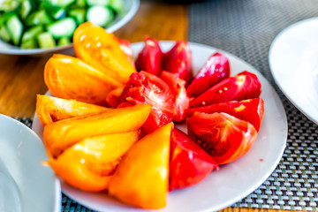 Fresh sliced juicy ripe red orange yellow vibrant vivid tomatoes slices on plate closeup table as healthy snack or salad appetizer