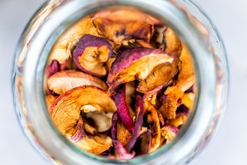 Flat top closeup of dehydrated orange colorful dry homemade pieces apple fruit slices stored in glass jar