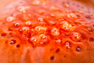 Closeup of red orange tomato soup or sauce boiling bubbling in pot macro closeup showing abstract detail texture surface