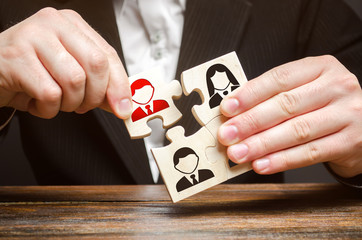 A businessman collects puzzles symbolizing a team of employees. The concept of the organization of...