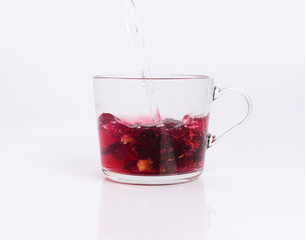 Pouring hot water to the glass cup with hibiscus tea, isolated on white background