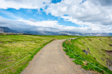 Fototapeta na wymiar Landscape trail hiking view near rocky beach in Hellnar, National park Snaefellsnes Peninsula, Iceland with green grass moss in summer day and clouds