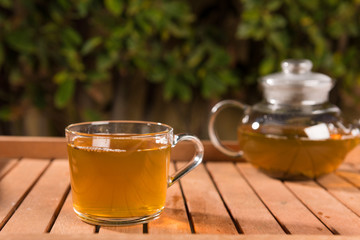 Cup of green tea on wooden table outdoors