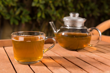 Cup of green tea on wooden table outdoors