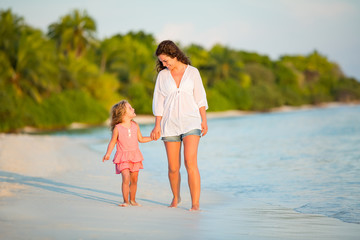 Mother and little daughter walking on sunny beach on Maldives at summer vacation