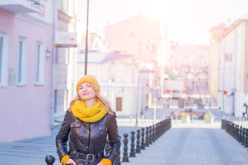 fashionable stylish girl in white beanie and knit jacket walking down the street and smiling