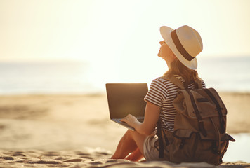 young woman working with laptop on nature in beach