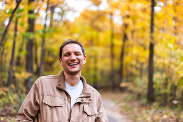 Virginia yellow orange autumn trees background in Fairfax County colorful foliage in northern VA on Sugarland Run Stream Valley Trail with happy man smiling laughing