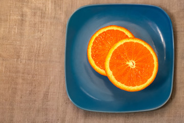 Citrus. A mandarin is served on a blue plate. A half tangerine or an orange on a table. Close-up. Soft focus. Top view. Copy space.