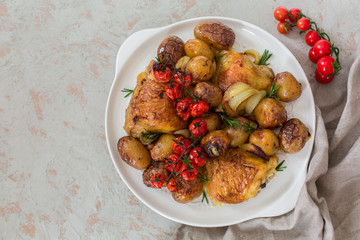 Roasted chicken thighs with baby potatoes, tomatoes, rosemary and onion