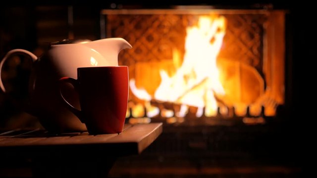 Blazing fireplace and a cup of tea. Cozy mood. Background