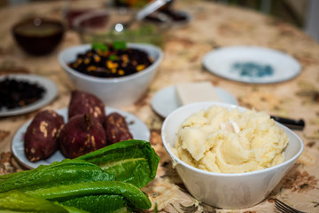 Table with setting of healthy vegan vegetarian Thanksgiving dinner and green vegetables romaine lettuce salad and mashed potatoes with sweet Japanese and plates in home dark