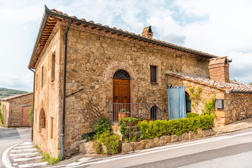 Fototapeta na wymiar Val D'Orcia countryside in Tuscany with empty street in small town village with nobody and plants on typical stone house in Querce al Pino, Italy