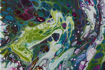 Close-up of abstract acrylic pour painting in purple, blue, and green.