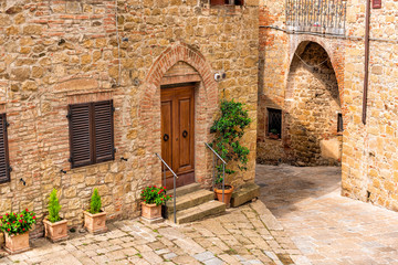 Monticchiello, Italy Val D'Orcia countryside in Tuscany with empty street in small town village and plants on typical stone house exterior