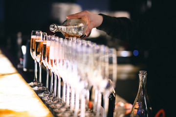 Bartender pouring champagne into row of glasses on a event