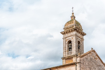 Fototapeta na wymiar San Quirico D'Orcia, Italy small historic medieval town village in Tuscany and famous church bell tower closeup isolated against sky