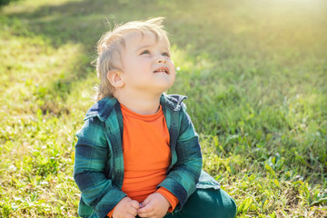 little blond boy on a green grass background on a Sunny day
